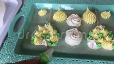 烹饪不同形状、颜色和大小的棉花糖放在托盘上。 女人用糕点袋添加了棉花糖的元素